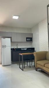 a kitchen with a couch and a table and a refrigerator at Loft amplo, apenas 6km do Morro do Careca! (G) in Natal