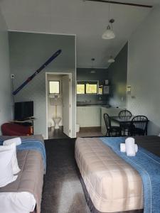 1 dormitorio con 2 camas y cocina con mesa en Ohakune Court Motel, en Ohakune