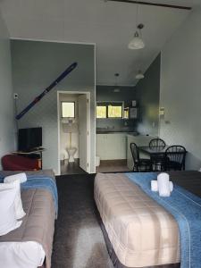 a bedroom with two beds and a kitchen with a table at Ohakune Court Motel in Ohakune