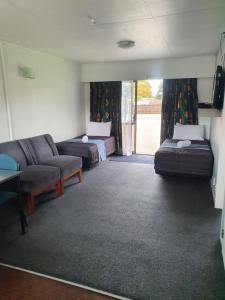 uma sala de estar com duas camas e um sofá em Ohakune Court Motel em Ohakune