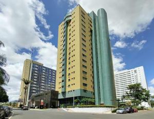 ブラジリアにあるQuartos em alto-padrão LETs IDEAの車が目の前にある街の高層ビル