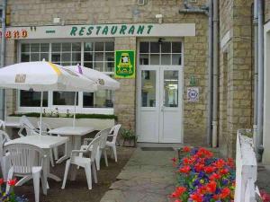 a restaurant with tables and chairs and an umbrella at Le Clos Normand in Troarn