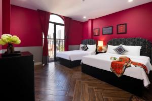 a bedroom with two beds and a red wall at Heritage Boutique Sierra Legend in Nha Trang