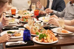 eine Gruppe von Menschen, die um einen Tisch mit Teller Essen sitzen in der Unterkunft Caravelle Saigon in Ho-Chi-Minh-Stadt