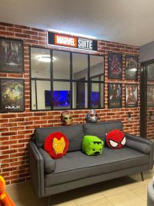 馬尼拉的住宿－Marvel Suite Staycation，砖墙上一张带超级英雄枕头的沙发
