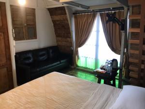 una camera con letto e divano in pelle di Villa Isabella Putri B&B a Jepara