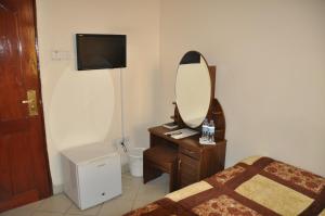 een slaapkamer met een spiegel, een bed en een dressoir bij Rich Hotel in Arusha