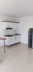 a kitchen with white cabinets and a black refrigerator at Apartaestudio Sendero Primavera in Neiva