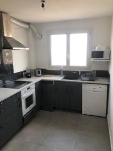 eine Küche mit schwarzen und weißen Geräten und einem Fenster in der Unterkunft Kennedy in Saint-Jean-de-Braye
