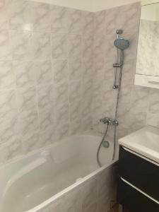 ein Badezimmer mit einer weißen Badewanne und einem Waschbecken in der Unterkunft Kennedy in Saint-Jean-de-Braye