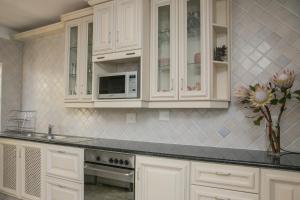 a kitchen with white cabinets and a microwave at Sunshowers Ballito in Ballito