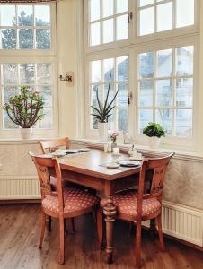 mesa de comedor con sillas y ventanas en Pension Jepsen, en Glücksburg