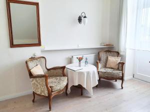 グリュックスブルクにあるPension Jepsenの椅子2脚、テーブル1台、鏡1台が備わる客室です。