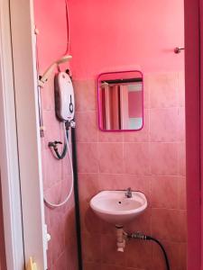 a pink bathroom with a sink and a mirror at Hotel Cahaya in Tanjung Malim