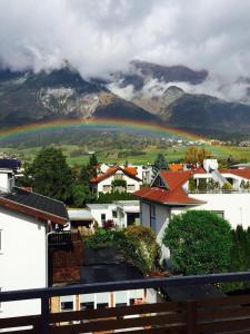 a rainbow over a city with mountains in the background at Citybergblick2 in Innsbruck