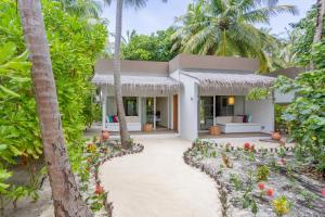 an exterior view of a villa with palm trees at Cocoon Maldives - All Inclusive in Lhaviyani Atoll