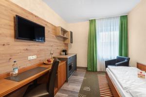 a hotel room with a desk and a bed at Schieners Hotel & Apfelhof Apartments in Wemding