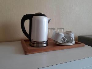 a coffee pot and cups on a wooden tray at Su's Cottages Legian in Legian