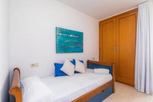 a bedroom with a bed with blue and white pillows at Angy Apartment in Alcudia