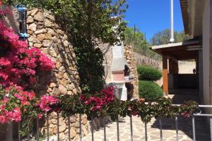 uma parede de pedra com flores ao lado de uma casa em Bella Vista With Sea View - Happy Rentals em Cugnana