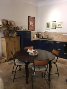 - une cuisine avec une table, des chaises et un évier dans l'établissement Coeur de l'Arquet, à LʼIsle-sur-la-Sorgue