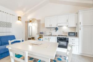 une cuisine avec une table blanche et un canapé bleu dans l'établissement Bella Vista With Sea View - Happy Rentals, à Cugnana