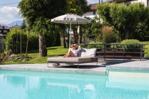 duas pessoas sentadas num sofá ao lado de uma piscina em Hotel Lisetta em Tirolo