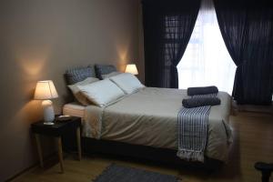 a bedroom with a bed with pillows and a window at Casa en Gregg -Exquisite 2-bedroom self catering unit - 1 car parking space in East London