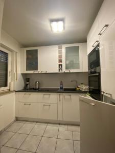 una cocina con armarios blancos y fregadero en Прекрасная квартира со всем необходимым для жизни en Duisburg