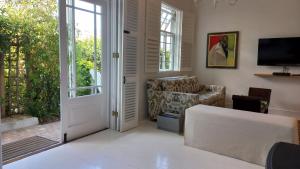 een woonkamer met een bank, een tv en een deur bij Willow Cottage in Kaapstad