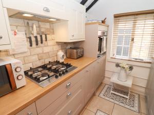 a kitchen with a stove top oven next to a window at Hobbes Cottage in Malmesbury +8 photos