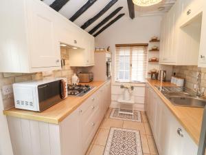 uma cozinha com armários brancos e um micro-ondas em Hobbes Cottage em Malmesbury