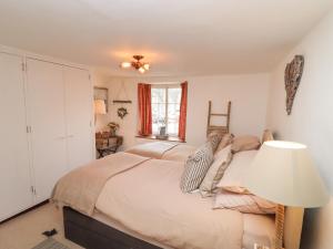 a bedroom with a bed with a lamp and a window at Hobbes Cottage in Malmesbury