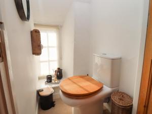 a bathroom with a toilet with a wooden seat at Hobbes Cottage in Malmesbury