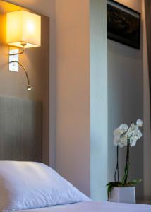 een slaapkamer met een bed en een vaas met bloemen bij Hôtel Restaurant La Chartreuse Logis de France in Cahors
