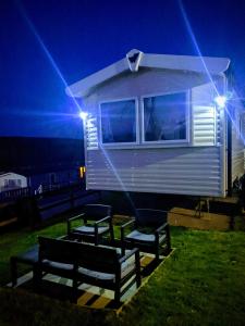 eine Gruppe Bänke vor einem winzigen Haus in der Unterkunft 4 Berth Couples and Family Caravan in Beautiful Newquay Bay Resort in Newquay