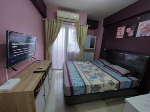 - une chambre avec un lit et un bureau avec une télévision dans l'établissement Green Pramuka Apartement By Vici, à Jakarta