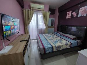 - une chambre avec un lit et une télévision à écran plat dans l'établissement Green Pramuka Apartement By Vici, à Jakarta