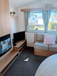 a living room with a couch and a flat screen tv at 4 Berth Couples and Family Caravan in Beautiful Newquay Bay Resort in Newquay