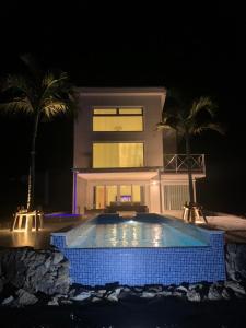 a swimming pool in front of a house at night at B BASE KOURI iSLAND in Kouri