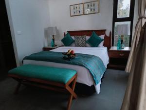 a bedroom with a large bed with green pillows at BluSalzz Escapade, Lansdowne - Uttarakhand in Lansdowne