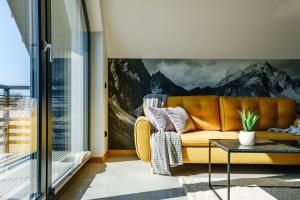 - un canapé jaune dans le salon orné d'une fresque murale de montagne dans l'établissement 285 Apartments, à Czarny Dunajec