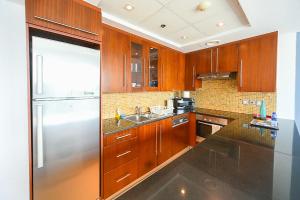 a kitchen with wooden cabinets and a stainless steel refrigerator at Chic Studio with a Balcony in Spectacular Downtown - NY in Dubai