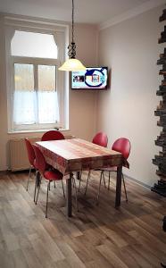 a dining room with a wooden table and red chairs at Ferienwohnung am Birkenwäldchen in Plauen