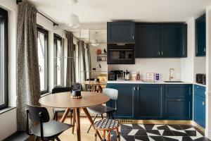 een keuken met blauwe kasten en een tafel en stoelen bij My Maison In Paris Invalides in Parijs