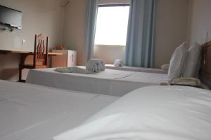 a hotel room with two beds and a window at Hotel Litoral in Aracaju