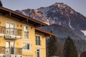 a yellow building with a mountain in the background at Hotel Schwabenwirt in Berchtesgaden