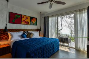 a bedroom with a blue bed and a large window at Cintacor Island Resort in Kārwār