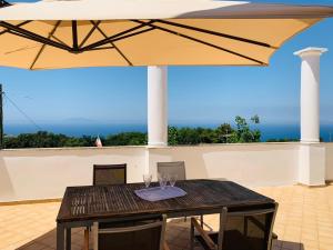 un tavolo con due bicchieri da vino sotto un ombrello di Casa Heather a Capri