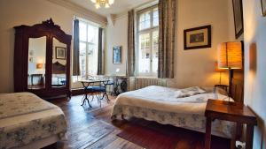 a bedroom with two beds and a mirror and a table at La Maison du Notaire Royal in Sarlat-la-Canéda +17 photos